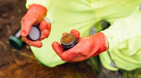 Engineer collecting a soil sample during a site investigation at a development plot